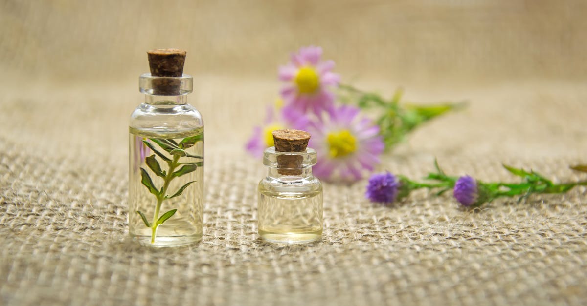 glass bottles with essential oils and fresh flowers on burlap fabric creating a natural aroma